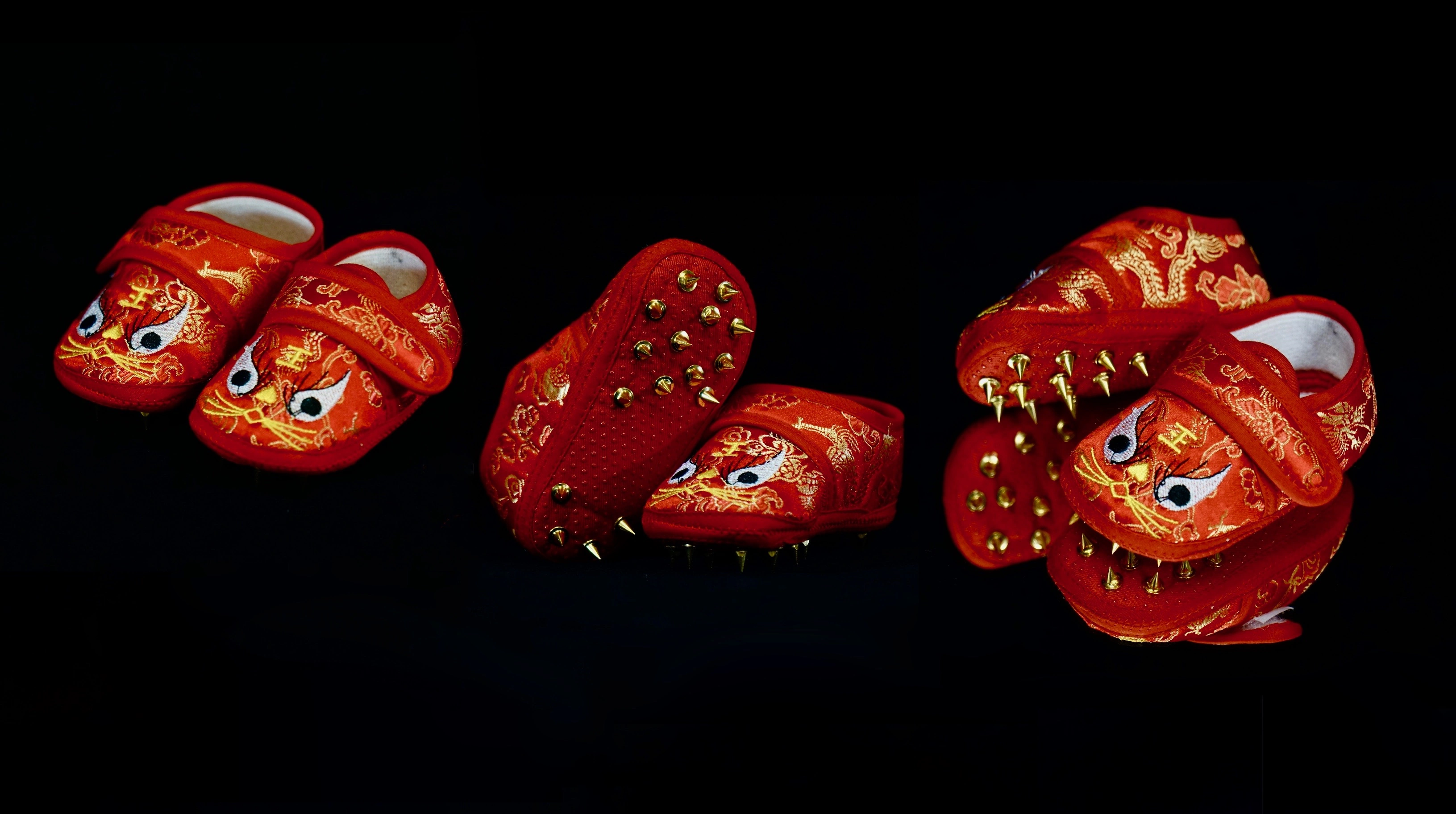 Red embroidered toddler shoes fitted with sharp silver track spikes.
