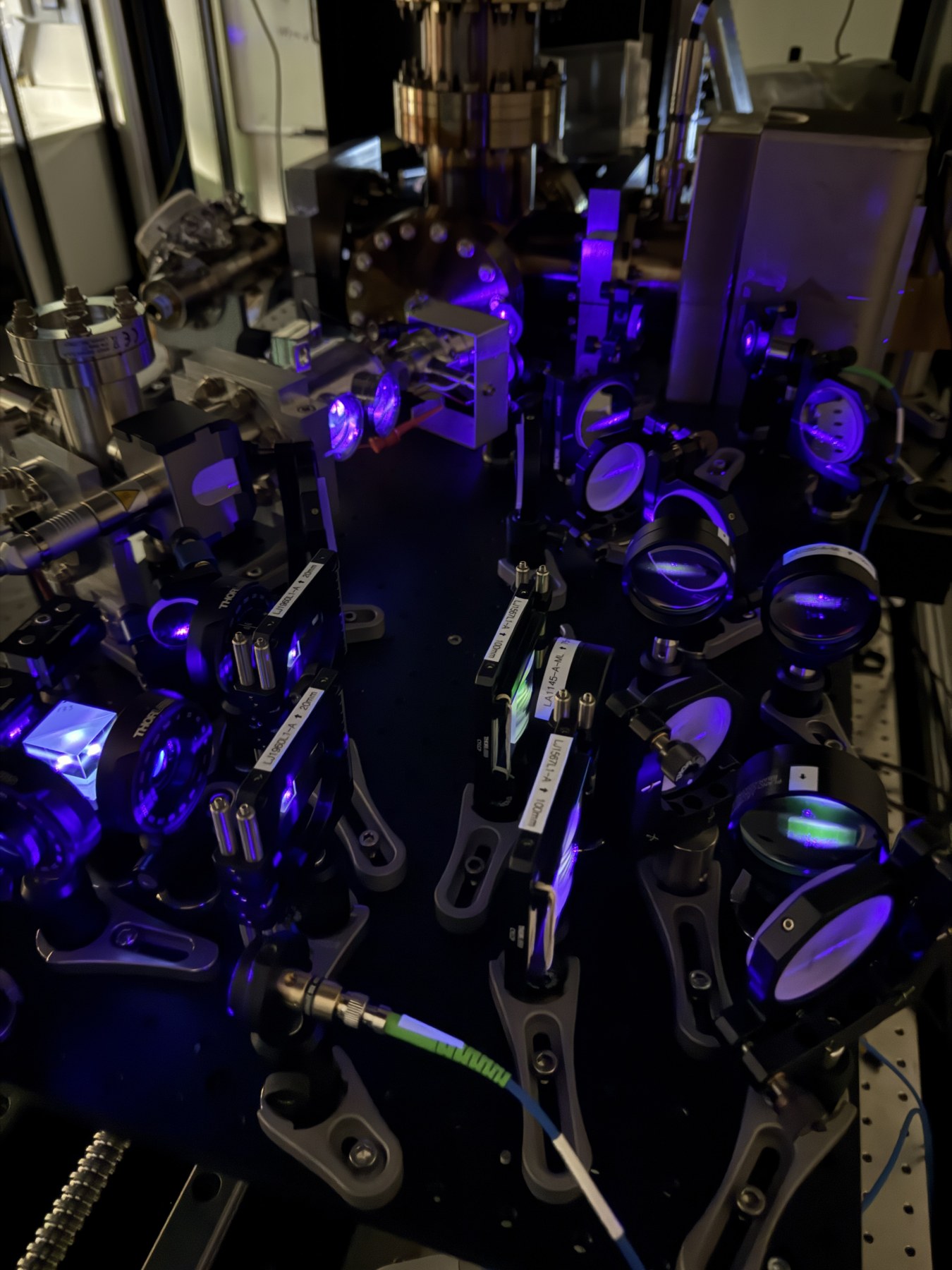 Optical table with lenses, mirrors, and violet laser light